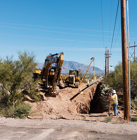 Caterpillar CAT D5K2 pipelayer holding pipe with CAT 316E excavator   Arizona